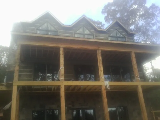 Dormers and porch framing on a large log home under construction — Roof Coating work by our crew in Lunenburg