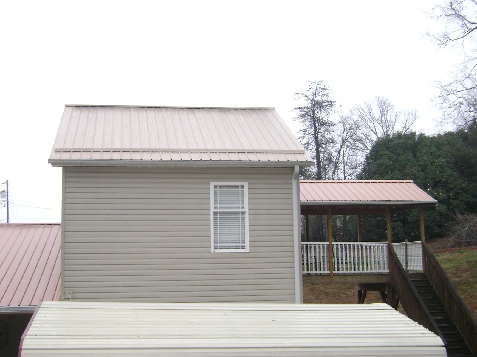 Tan metal roofs on a two story addition and attached porch, from a Roof Replacement job in Lunenburg