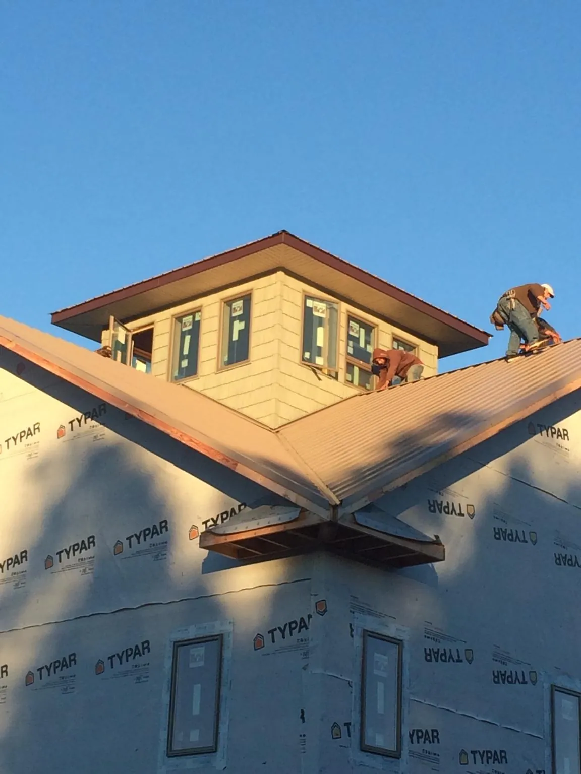 Roofers working around a rooftop cupola on a new metal roof at sunset — Roof Waterproofing in Lunenburg by Roofing Brothers